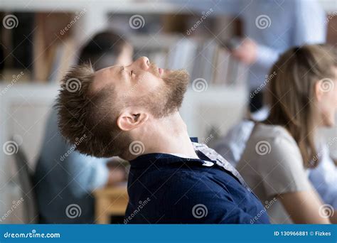 Tired Male Employee Falling Asleep In Chair At Workplace Stock Image