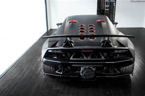 The Rear End Of A Black Sports Car Parked In A Room With Wood Flooring