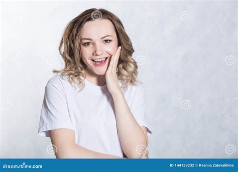 Amazed Young Woman Looks With A Smile And Surprise Presses Hand To