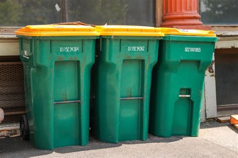 Premium Photo | A row of green and yellow trash cans are lined up on a ...