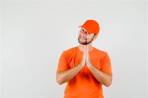 Free Photo Delivery Man In Orange T Shirt Cap Holding Hands In