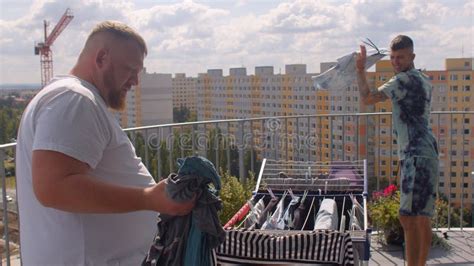 A Gay Couple Hangs Up The Laundry On The Balcony To Dry Stock Image Image Of Bisexual Male