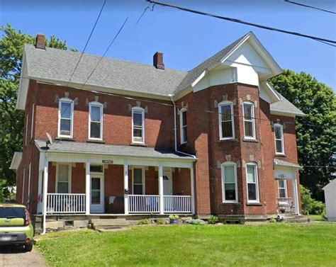 A Large Red Brick House Sitting On The Side Of A Road