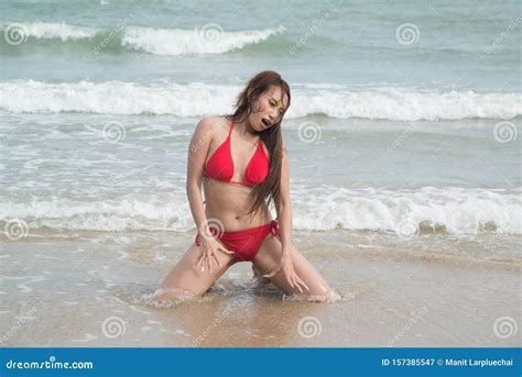 Une Femme Asiatique En Bikini Rouge Pose Un Si Ge Sur La Plage Image