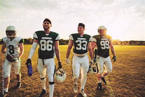 Smiling Team Of American Football Players Walking Off A Field Stock