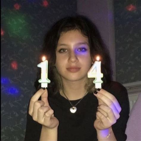 A Woman Holding Two Candles In Front Of Her Face With The Number One On