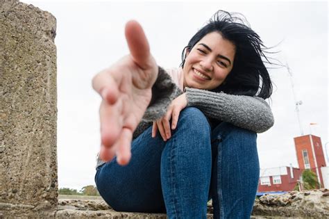 Vista Frontal De Una Joven Latina Al Aire Libre Sentada Feliz Con El