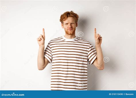 Skeptical Handsome Redhead Man Pointing Fingers Up Grimacing And