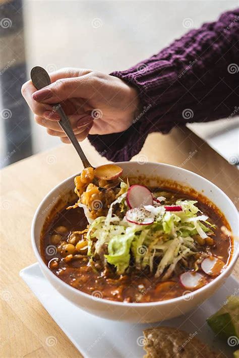 Vertical Shot Of A Woman Hand Taking A Spoonful Of Mexican Pozole From