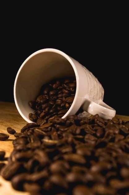 Taza blanca rebosante de granos de café tostados Foto Premium