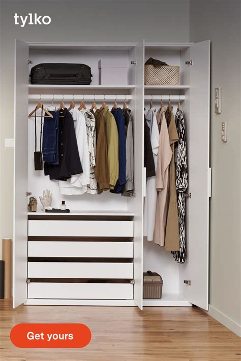 An Open White Closet With Clothes Hanging On The Rail And Shoes In The