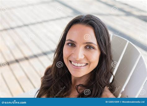 Pretty Brunette Sitting On A Chair And Smiling At Camera Stock Image