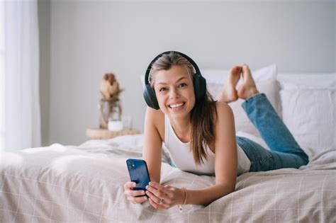 Emocionada Joven Hispana Adulta Acostada En La Cama Usando Auriculares