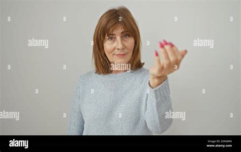 A Mature Woman With Short Hair Makes An Inviting Gesture Against A White Background Stock Photo