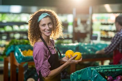 Premium Photo Smiling Female Staff Holding Fruits In Organic Section