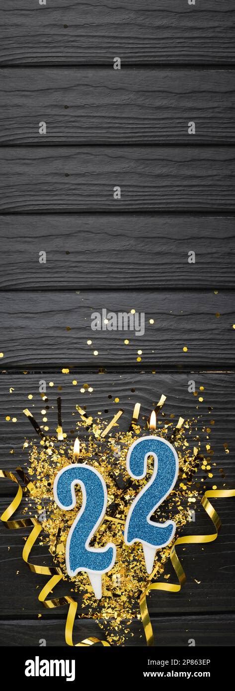 Number 22 Blue Celebration Candle And Gold Confetti On Dark Wooden