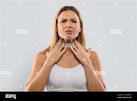 Unhappy Blonde Woman Touching Her Neck Checking Adenoids Stock Photo