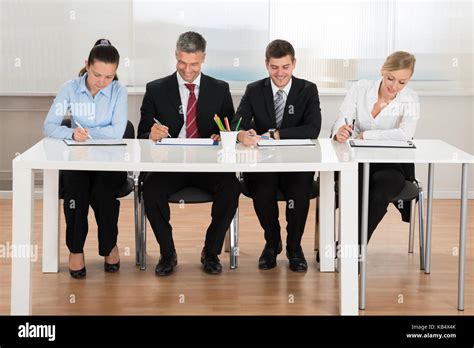 Happy Businesspeople Writing On Clipboard At Desk Stock Photo - Alamy
