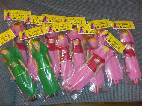 There Are Many Barbie Dolls In Plastic Bags On The Bed With Tags