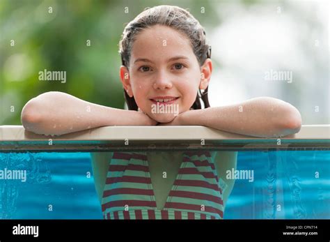Chica en Bikini recostada sobre el borde de la piscina sonriente Retrato Fotografía de stock