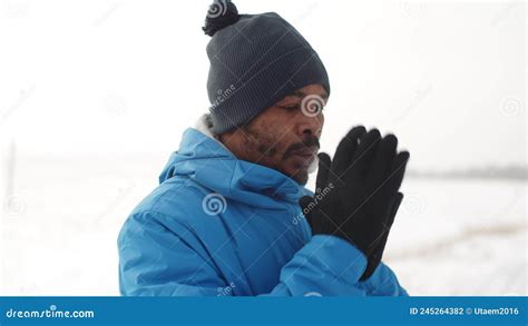 Black Man In Winter Clothes Warm Gloved Hands With His Breath And