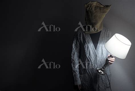 Woman With Burlap Bag On Her Head Standing In A Dark Room With