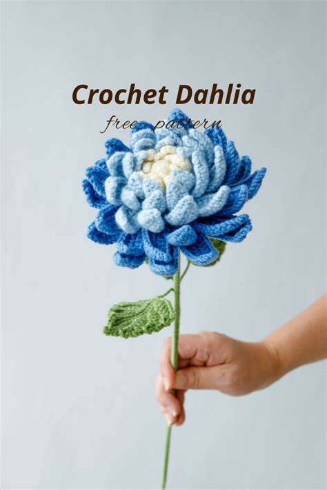 A Crochet Dahlia Flower Is Being Held By A Person S Hand