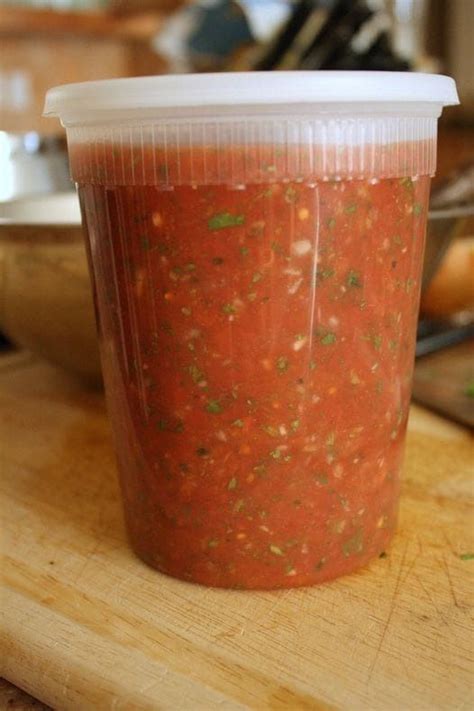 A Plastic Cup Filled With Salsa Sitting On Top Of A Wooden Table