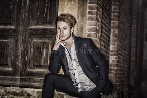 Attractive Young Blond Man Hiding Half Face Behind Wall Stock Image