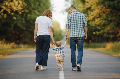 Los Padres Que Sostienen A Su Pequeño Hijo Están Caminando Por Un