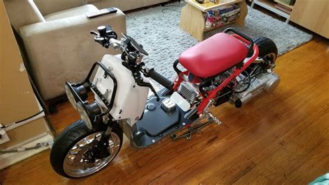 A Small Red And White Motorcycle Parked In A Living Room Next To A