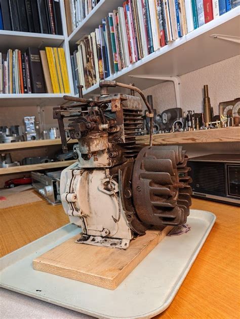 An Old Engine Sitting On Top Of A Wooden Table In Front Of Bookshelves