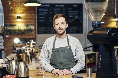 Portrait Of Young Male Barista At Coffee Shop Kitchen Counter Stock Photo