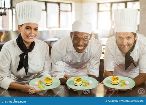 Portrait Of Smiling Chefs Team Holding Dessert Plates Stock Image