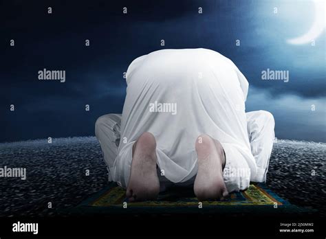 Close Up View Of A Muslim Man In A Praying Position Salat On A Prayer Rug With A Night Scene