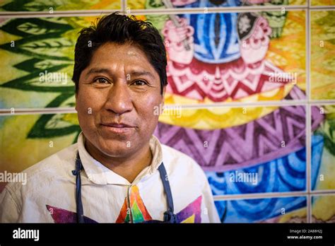 Portrait Of Aymara Indigenous Artist Roberto Mamani Mamani With One Of His Paintings In His