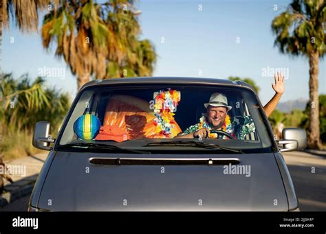 Happy man driving car waving hand through window Stock Photo - Alamy