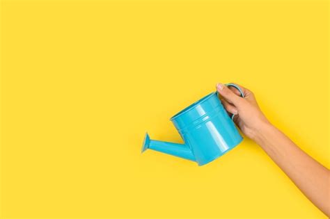 Premium Photo Woman Hand Holding A Watering Can On A Yellow Background