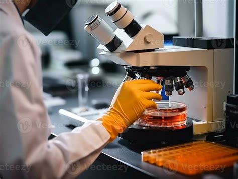 Technician Analyzing Blood Sample At Laboratory With Microscope In