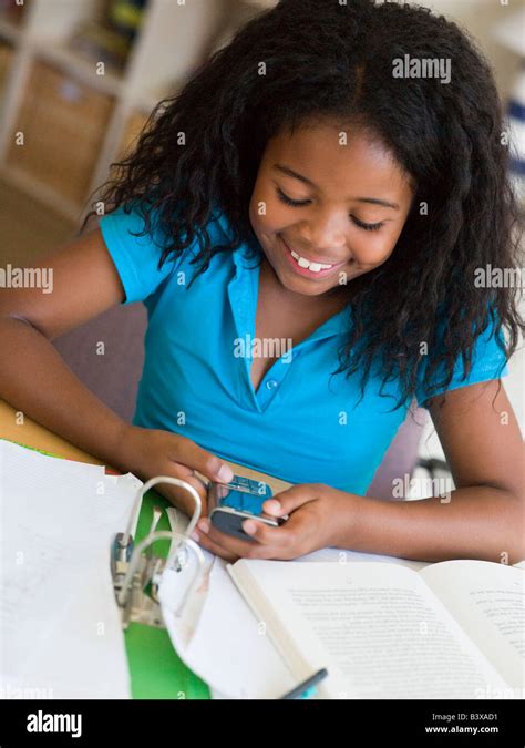 Young Girl Distracted From Her Homework Playing With A Cellphone Stock