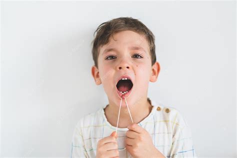 Premium Photo Cute Boy Pulling Loose Tooth Using A Dental Floss