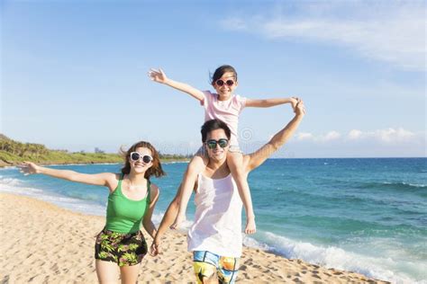 Famille Heureuse Sautant Sur La Plage Au Coucher Du Soleil Image Stock