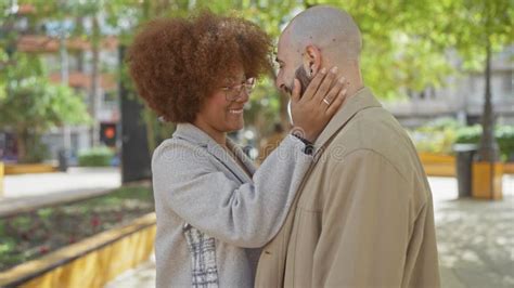 Interracial Couple Embracing Joyfully In A Sunny Urban Park Stock