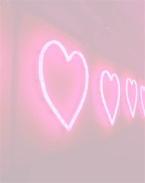 Three Neon Hearts Are On The Wall Next To Each Other