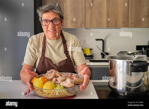 Happy mature Spanish woman showing homemade cocido madrileño typical