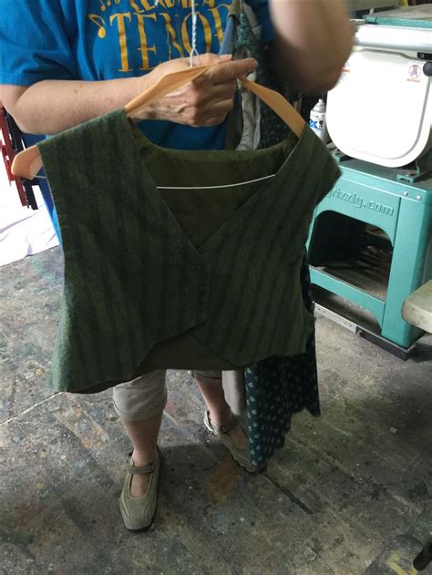 A Man And Woman Looking At An Old Sweater On A Hanger In A Shop