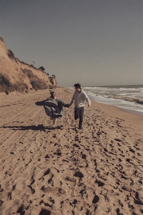 Man And Woman Enjoy Each Other Run Along The Seashore Stock Photo