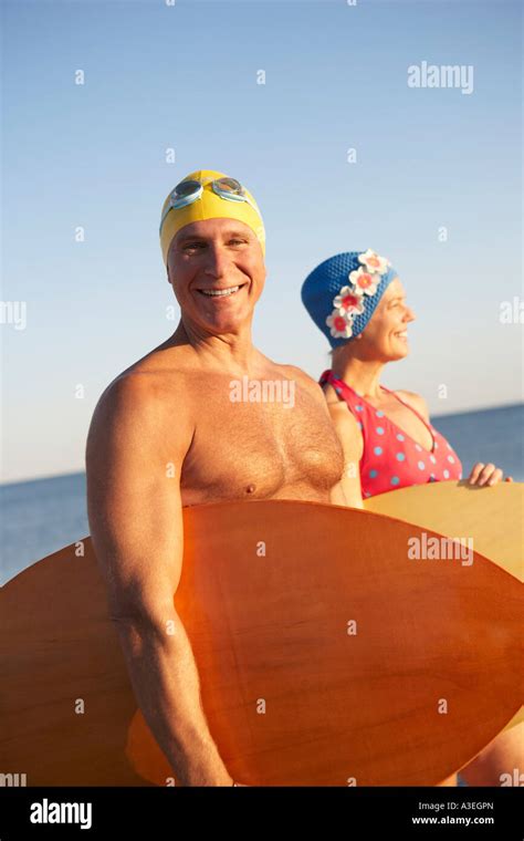 Portrait Of A Mature Man With A Mature Woman Holding Surfboards On The