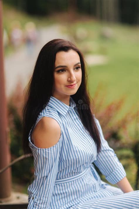 Lady In Blue Dress Sitting On The Bench Near The Lake Stock Photo