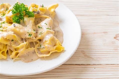 Pasta tortellini con salsa de crema de champiñones y queso Foto Premium